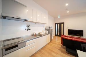 cocina con armarios blancos, fregadero y TV en Yufusouin - Vacation STAY 85705, en Yufu