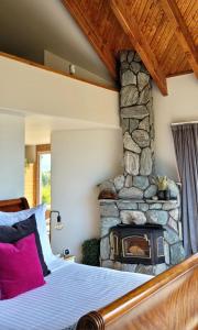 a bedroom with a stone fireplace next to a bed at Rose Ridge Retreat in Upper Moutere