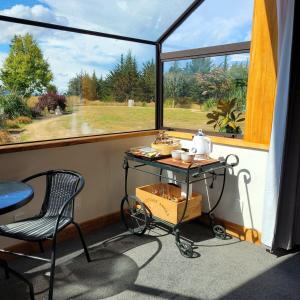 a screened in porch with a table and a window at Rose Ridge Retreat in Upper Moutere +28 photos