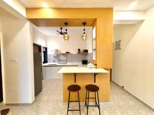 a kitchen with two bar stools and a counter at Relaxing 2BHK with Mangrove View - Family-Friendly, Pool - Candolim Beach in Candolim