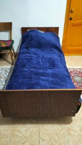a bed with a blue blanket on top of it at Хостел Москва in Aktobe +3 photos