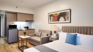 Un dormitorio con una cama y una silla y una cocina. en Savea Bay City Manila, en Manila