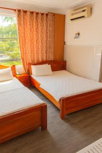 two beds in a room with a window at Hải Quỳnh Hotel in Ho Chi Minh City