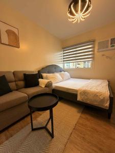 a bedroom with a bed and a couch at Urban Oasis Cozy Studio at Berkeley Suites South Forbes Nuvali in Silang