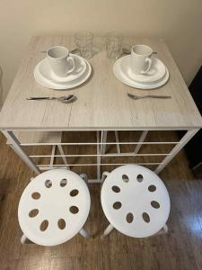 a wooden table with two chairs and two cups and plates at Urban Oasis Cozy Studio at Berkeley Suites South Forbes Nuvali in Silang
