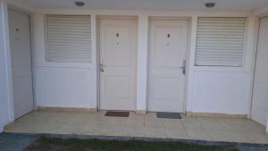 two white doors on a building with a tile floor at Habitación en 25 in Veinticinco de Mayo