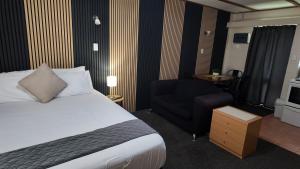 a hotel room with a bed and a chair at Bay Lodge Motel in Tauranga