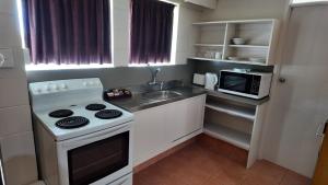 a small kitchen with a stove and a microwave at Bay Lodge Motel in Tauranga +8 photos