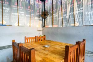 a wooden table with two chairs and a table with books at RedDoorz at MG House Siantar Timur in Pematangsiantar