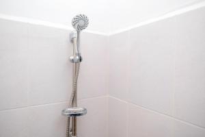 a shower with a shower head in a bathroom at RedDoorz at MG House Siantar Timur in Pematangsiantar +42 photos