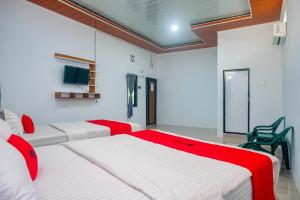 two beds in a room with red and white at RedDoorz at MG House Siantar Timur in Pematangsiantar