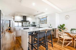 a kitchen with white walls and a large island with bar stools at Shara Seaside Oasis - Alex Beach 3BD Apartment in Alexandra Headland