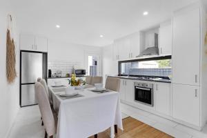 a white kitchen with a white table and chairs at California 'Luxe Boho' with Pool in Echuca