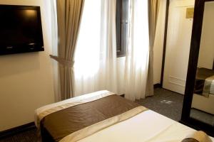 a bedroom with a bed and a window and a television at The Inn at Temple Street in Singapore