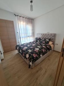 une chambre avec un lit avec une couette fleurie dans l'établissement Cozy 2 Bedroom Prestigia - close to Plage des Nations, à Sidi Bouqnadel