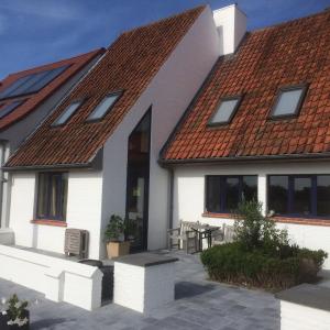 une maison blanche avec un toit rouge et une terrasse dans l'établissement Holiday Home Denolijfboom, au Coq