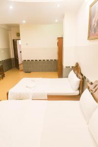 twee bedden in een kamer met witte lakens bij Tân Ty Mon Hotel in Ho Chi Minh-stad