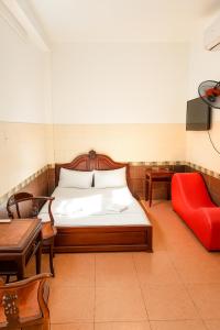 een slaapkamer met een bed en een rode stoel bij Tân Ty Mon Hotel in Ho Chi Minh-stad