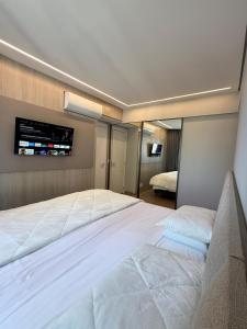a bedroom with a large bed with a tv on the wall at Savassi Luxury 2BR Pool and Home Office in Belo Horizonte