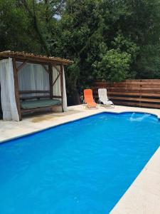a blue swimming pool with two chairs and a gazebo at Cabaña La Pintoresca in Capilla del Señor