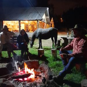 een groep mensen die rond een vuur zitten met een paard bij Quinta Rincon Chagra in Cevallos