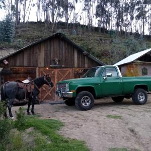 een groene vrachtwagen met een paard dat naast een gebouw staat bij Quinta Rincon Chagra in Cevallos