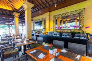 a restaurant with tables and chairs and a bar at Griya Santrian a Beach Resort And Spa in Sanur