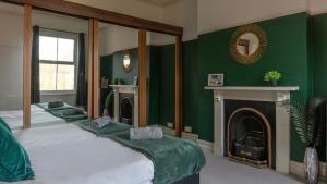 ダービーにある6 BDR House By Eason Stays Short Lets & Serviced Accommodation Derby With Free Parkingの緑豊かなベッドルーム(大型ベッド1台、暖炉付)