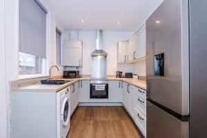 une cuisine avec des armoires blanches et un réfrigérateur en acier inoxydable dans l'établissement Four BR House By Eason Stays Short Lets & Serviced Accommodation Worsley With Free Parking, à Worsley