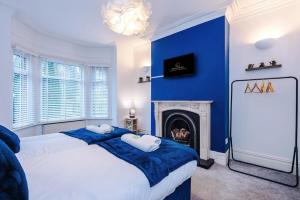 une chambre bleue avec un lit et une cheminée dans l'établissement Four BR House By Eason Stays Short Lets & Serviced Accommodation Worsley With Free Parking, à Worsley