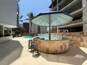 a patio with an umbrella and a table and chairs at 509 Flat praia piscina barzinho Intermares in Cabedelo