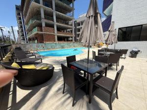 a pool with chairs and a table with an umbrella at 509 Flat praia piscina barzinho Intermares in Cabedelo