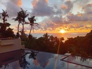 a sunset over the ocean from a swimming pool at Alon stay in Baras +9 photos