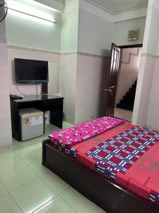 a bedroom with a bed and a desk and a television at Khách Sạn Giang Phước Hùng in Ho Chi Minh City