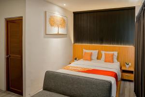 a bedroom with a large bed with orange pillows at Jember Town Square by Calli Rooms in Wirolegi