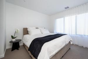 a white bedroom with a large bed and a window at Villa Capri - Luxe Modern by the Village in Mount Eliza