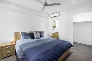 a bedroom with a blue bed with a ceiling fan at Marina Retreat in Sandstone Point +16 photos