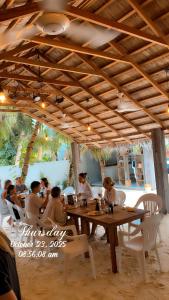 a group of people sitting at a table in a restaurant at The Palm Ray Rasdhoo in Rasdu