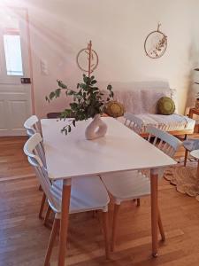 Ainay-le-ChâteauにあるAppartement cosy 70 m2 tout confort 4 personnesの白いダイニングテーブル(白い椅子付)、花瓶