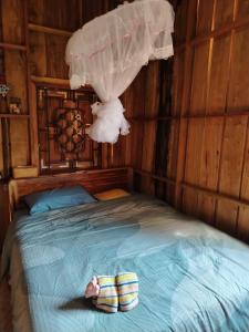a bedroom with a bed with a doll laying on it at Saneehaa Homestay Resort in Ban Sibouhuang