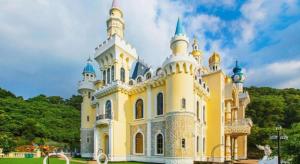 a large yellow and white building with blue turrets at Dongguan Castfast Hotel in Qinglinjing