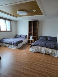 two beds in a room with wooden floors at Yeoncho Money Stay in Geoje 