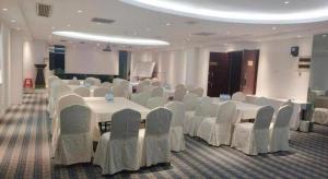 a conference room with white tables and chairs in a room at Wanyi Hotel in Dongguan