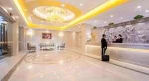 a man standing in a hotel lobby with a suitcase at Vienna Hotel Chengdu Chunxi Road Lijiatuo Metro Station in Chengdu
