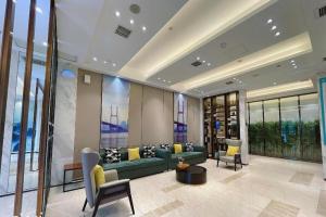 a living room with a green couch and some windows at City Comfort Inn Wuhan University Guangbutun Metro Station in Wuhan
