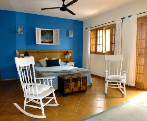 a bedroom with blue walls and a bed with two chairs at Kira's Boutique Hotel in Mindelo
