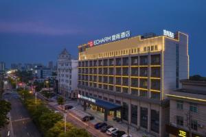 a building with a sign on top of it on a city street at Echarm Hotel Jingjiang Bus Passenger Station Fanggu Street in Jingjiang