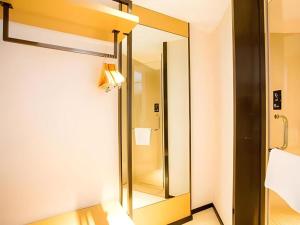 a bathroom with a mirror and a light on the wall at City Comfort Inn Guilin Yangshuo Shili Hualang Qianguqing in Yangshuo +41 photos