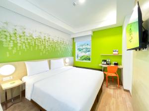 a bedroom with a white bed and a green wall at Zest Ambon by Swiss-Belhotel International in Ambon