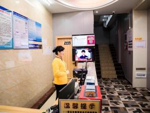 a woman standing in a lobby with a television at Shell Hotel Jiangxi Fuzhou Linchuan Avenue in Shiliting